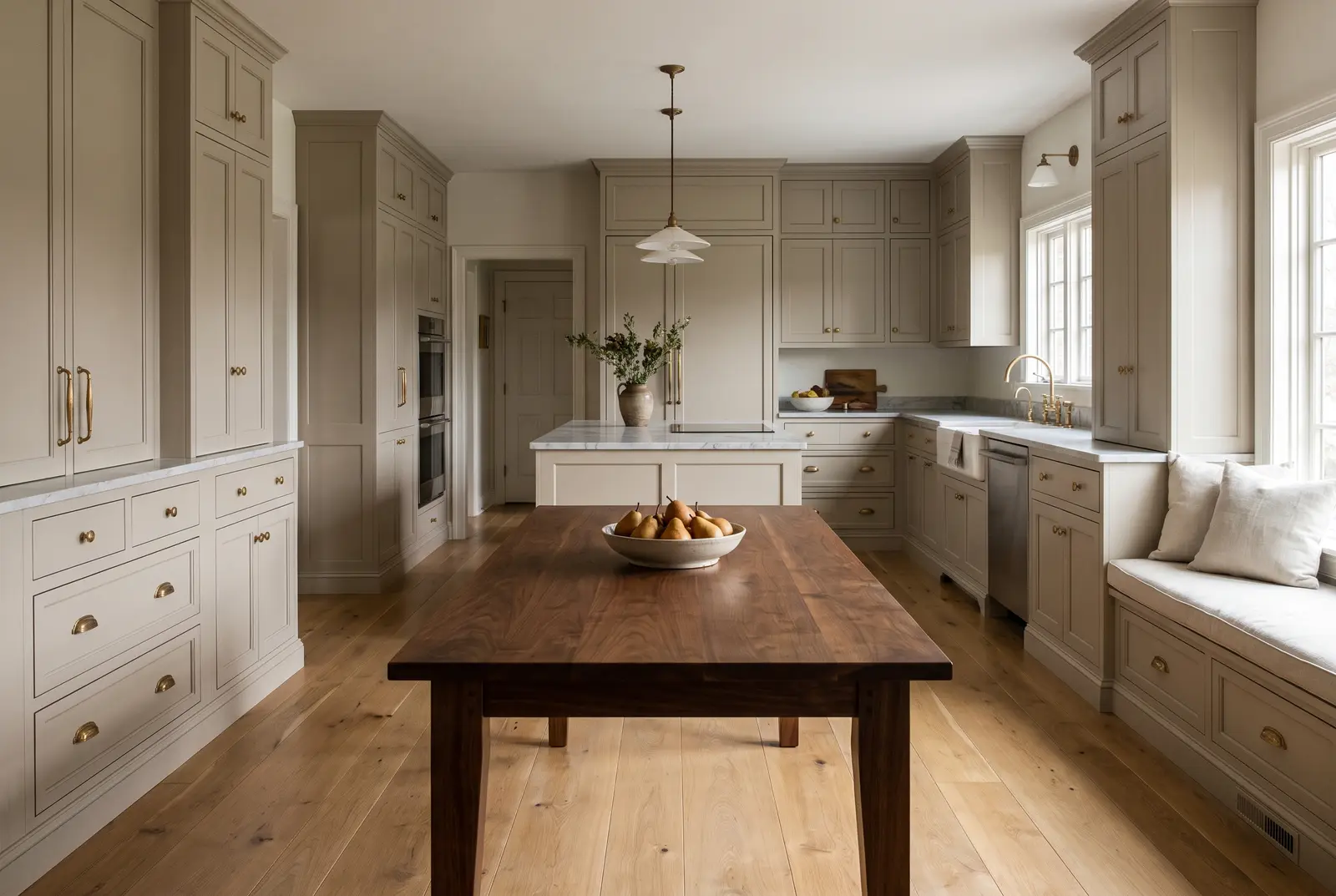 A painted-millwork kitchen with a walnut table, a bowl of pears and oak floors in afternoon light
